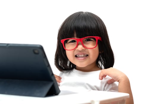 Happy little Asian Preschooler girl wearing red glasses and using tablet pc on white background and smile, Asian girl learning with a video call with tablet, Educational concept for school kids photo