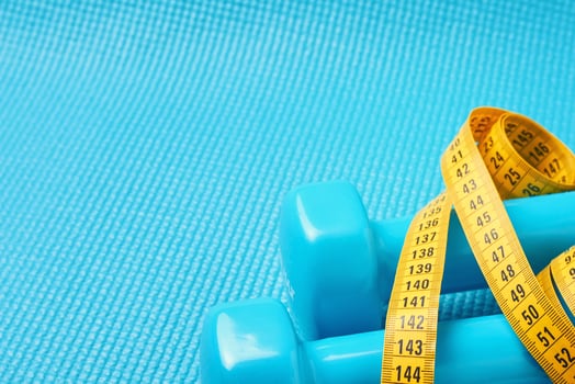 Fitness concept. Dumbbells and tape measure on a blue background with copy space. photo