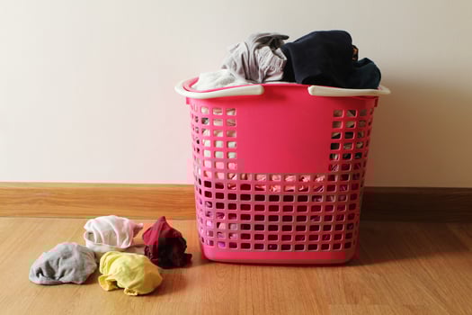 Basket with dirty laundry on the wooden floor in room. photo