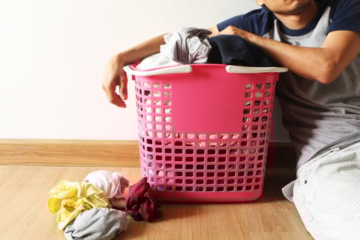 Basket with dirty laundry on the wooden floor in room and a man is leaning against it with fatigue. photo
