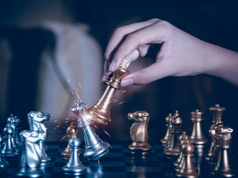 Hand businessman moving the golden knight chess fighting silver knight with fire sparks chess on chess board to successfully in the competition. Management or leadership strategy and teamwork concept. photo
