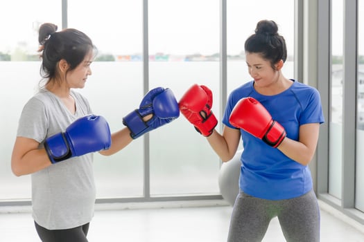 Two middle-aged Asian women doing boxing exercises in the gym. photo