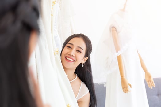 An Asian bride is choosing a dress for her wedding, standing smiling brightly for the friends that come together. photo