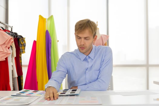 Professional male sewing designers in the office have a variety of fabric color schemes. photo