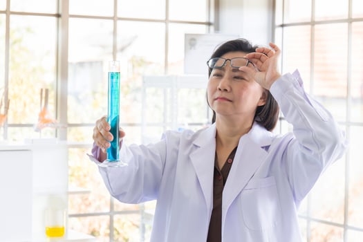 Discovering a cure for an Asian female scientist who is concentrated, holding a test tube and watching while working. photo