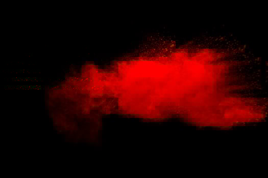 Abstract red dust explosion on black background. Freeze motion of red powder splash. photo