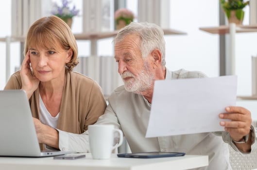 Worried senior couple checking their bills, retired elderly old family reading documents photo