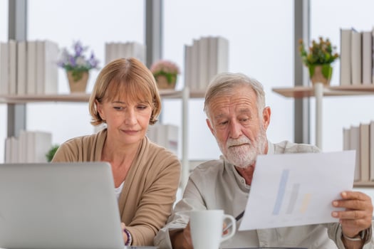 Worried senior couple checking their bills, retired elderly old family reading documents photo