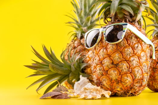 Creative pineapple looking up with sunglasses and shell isolated on yellow background, summer vacation beach idea design pattern, copy space close up photo