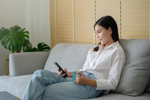 Young happy woman relaxing and using smart phone at home, social media and technology concept. photo