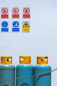 Gas cylinder tanks with various warning sign on white cement wall in safety zone area photo