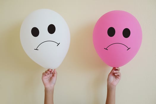 Close up hand's kid holding the sadly face white and pink balloons on yellow wall background. Realistic balloon. Thinking concepts. Emotional concept. photo