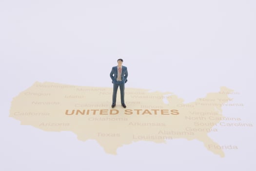 Miniature people, businessman standing on map American photo