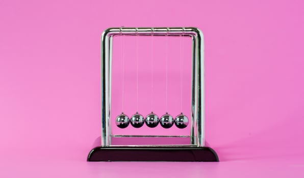 Newton's cradle physics concepts for action and reaction or cause and effect On the pink background photo