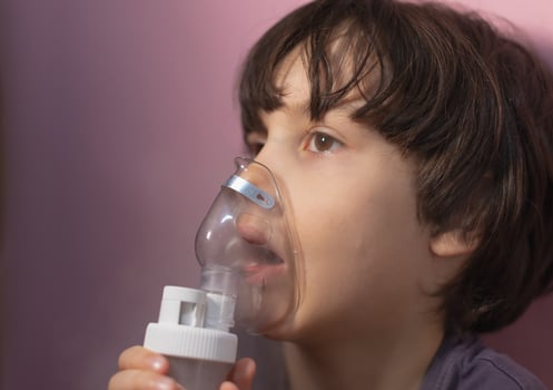 the child does inhalation, the boy inhales the medicine through the mask photo