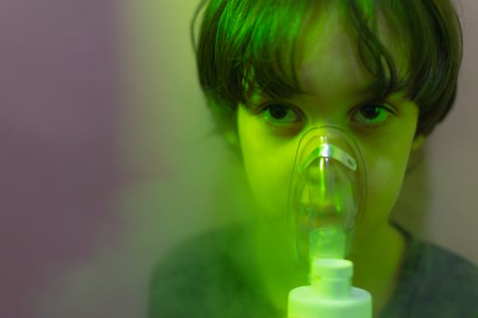 the child does inhalation, the boy inhales the medicine through the mask photo
