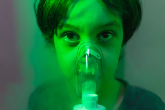 the child does inhalation, the boy inhales the medicine through the mask photo