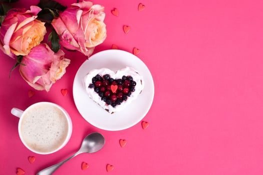 Heart shaped cake decorated with red currant on pink back photo