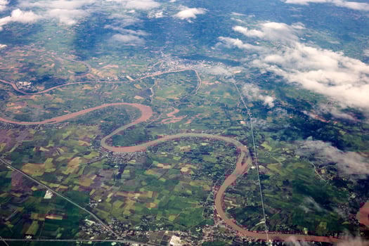 aerial photo from window of plane, above ground and cloud, green field under the clouds