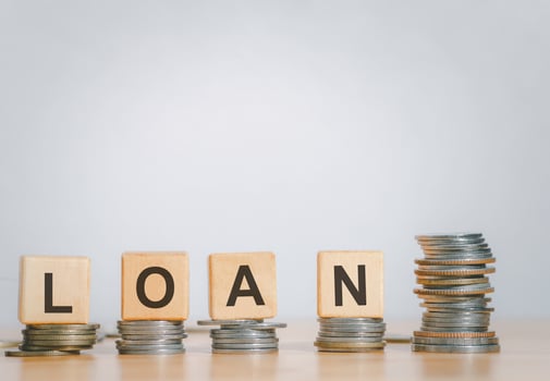 Close Up wooden block written LOAN against on stack coins to business and finance concept. Fees and Interest from loans are main revenue for banks. Loans can be unsecured such as credit card. photo