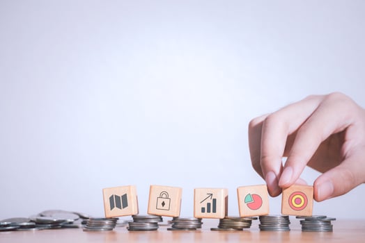 Hand of business strategy or e-commerce taking wooden blocks with target, padlock and graphs icons laying on stack coins or real money  .Business achievement goal,growth success and benefits concept. photo