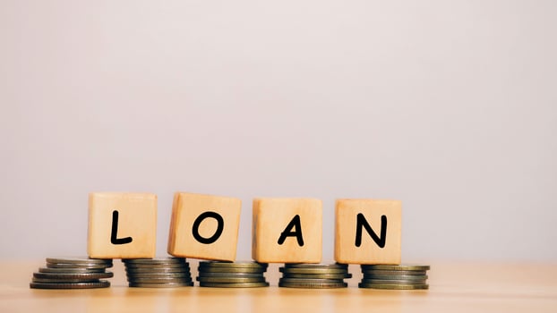 Close Up wooden block written LOAN against on stack coins to business and finance concept. Fees and Interest from loans are main revenue for banks. Loans can be unsecured such as credit card. photo