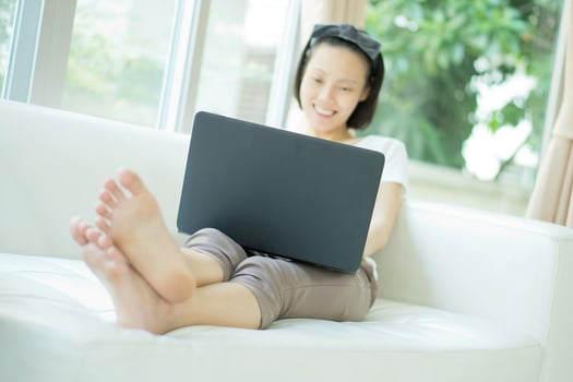 Casual young woman using laptop in living room at home photo