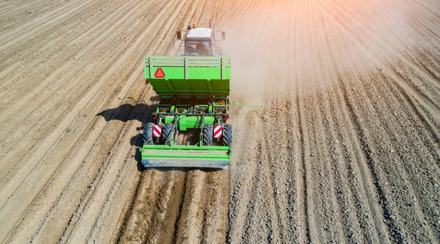 A farmer and tractor in the field planting potatoes in the fertile farm fields. Aerial view. photo