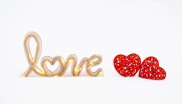 Word love in the snow with fairy lights the glow of garlands on a rope of jute  and two red hearts - greeting card for Valentine's Day, holiday February 14. Copy space. Invitation to a date photo