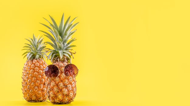 Creative pineapple looking up with sunglasses and shell isolated on yellow background, summer vacation beach idea design pattern, copy space close up photo