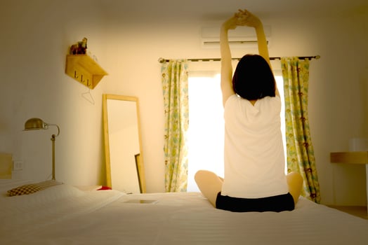 Woman stretching in her bed, rear view photo