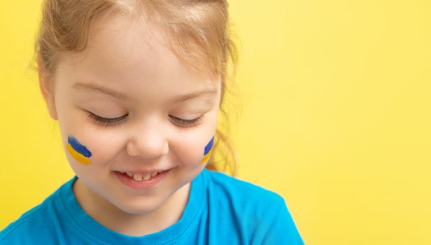 Smiling girl with a painted Ukrainian flag of yellow and blue on her cheeks photo