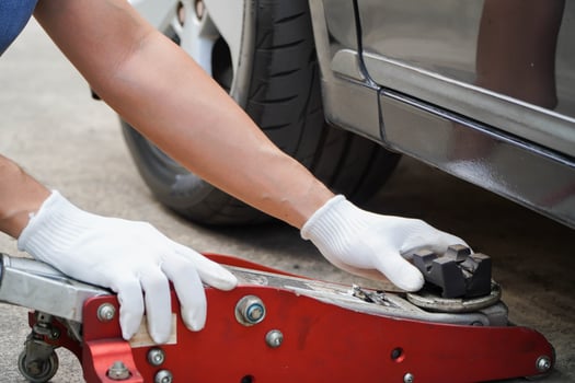 mechanic uses the jack to lift the car to fix the car's suspension. photo