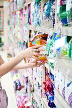 Positive woman choosing detergent in laundry section of supermarket photo