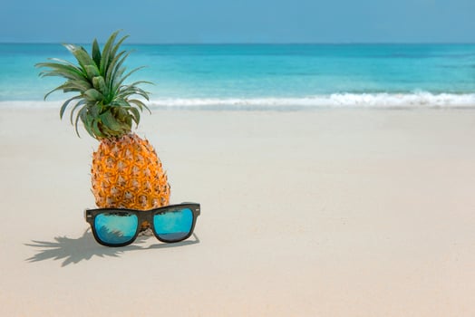 Pineapple fruit in sunglasses on sand against turquoise caribbean sea water. Tropical summer vacation concept photo