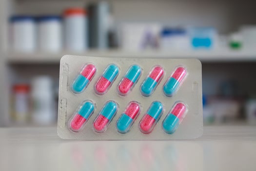 colorful capsules pills with blur shelves of drug in the pharmacy drugstore background photo