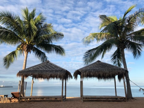 Two small huts on beach palm trees background photo