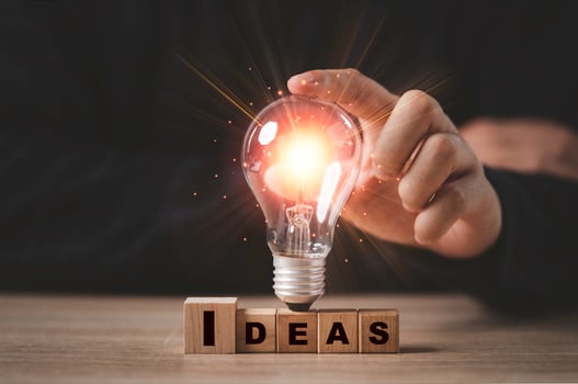 Businessman touching glowing light bulb on Idea wording print screen to wooden cube block for creative idea thinking and innovation concept. photo