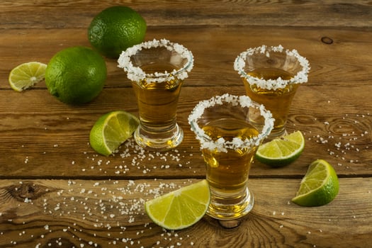 Three tequila shots with lime and salt on the wooden background photo