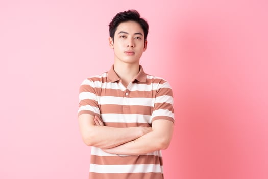 Young Asian man posing on pink background photo