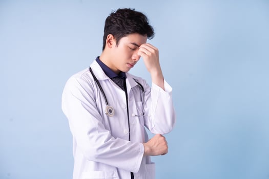 Portrait of young Asian male doctor on blue background photo