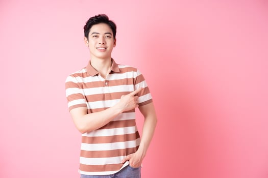 Young Asian man posing on pink background photo
