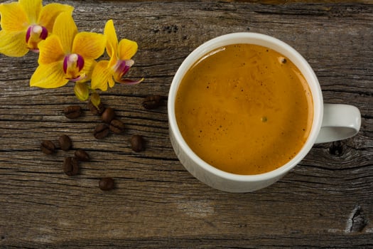 Coffee mug and yellow  orchid on the wooden background photo
