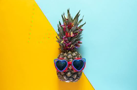 A smart pineapple in sun glasses and bright beads.Minimal concept, summer tropical pineapple. photo