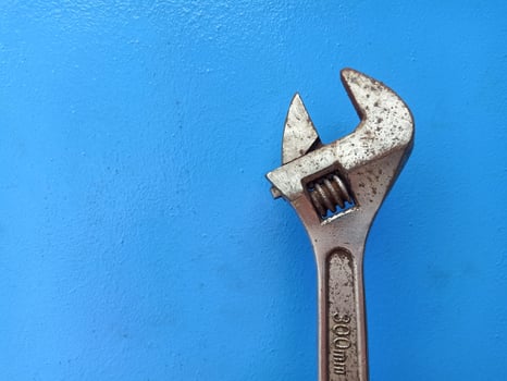 Rusty Adjustable Wrench isolated on blue background, copy space concept for industrial work and mechanical tools photo