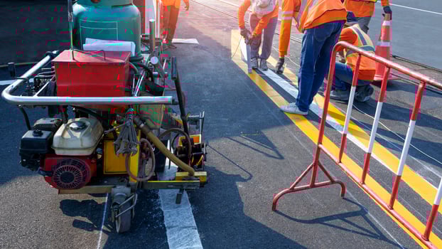 Road workers group with thermoplastic spray road marking machine are working to paint traffic lines on asphalt road with railway track crossing on street surface photo