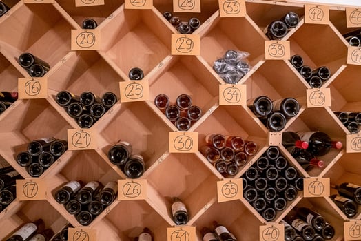 Variety of wine in glass bottles on wooden racks with numbers in supermarket photo