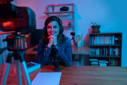 Beautiful Hispanic woman in front of a video camera recording a blog in her studio with red and blue lights inside her house photo