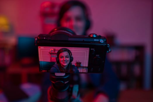 Beautiful Hispanic woman in front of a video camera recording a blog in her studio with red and blue lights inside her house photo