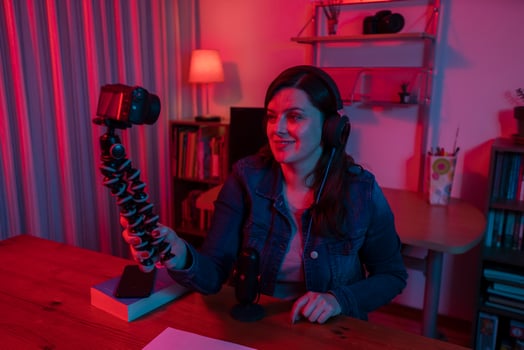 Beautiful Hispanic woman in front of a video camera recording a blog in her studio with red and blue lights inside her house photo